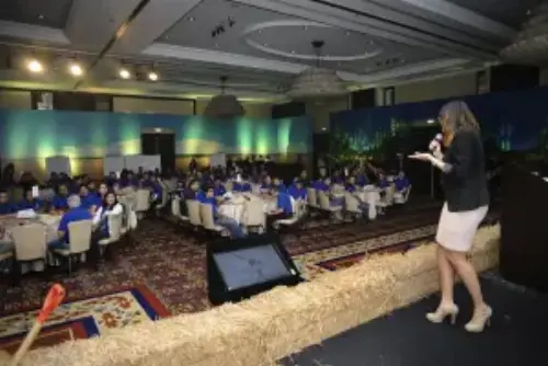 This picture shows a group of listeners as well as one person holding a speech on a corporate event.