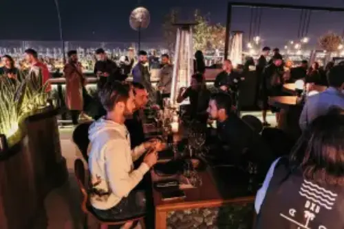 This picture shows guests of an event on a rooftop, having dinner in a chic environment.
